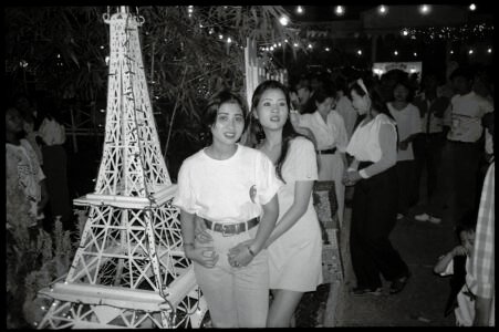 Documentary portrait of young women posing for a photograph with a model of the Eiffel Tower in Saigon by Spiros Coutroubas, Vietnam, 1996 Vietnam 1996: portrait of young women posing for a photograph with a model of the Eiffel Tower in Saigon, by Spiros Coutroubas - part of a series of documentary photographs of people and places in Vietnam in the 1990s
