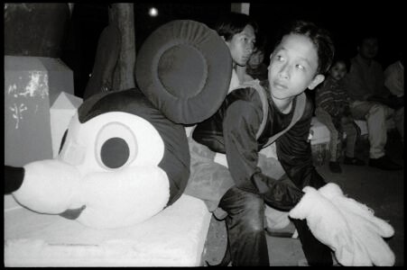 Photographic portrait of a boy on a break from working as Mickey Mouse,by Spiros Coutroubas, Ho Chi Minh City, Vietnam, 1996 Vietnam 1996: portrait of a boy on a break from working as Mickey Mouse, by Spiros Coutroubas - part of a series of documentary photographs of people and places in Vietnam in the 1990s