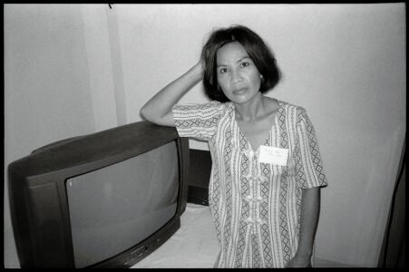 Photographic portrait of a woman with a TV by Spiros Coutroubas, Thu Duc District, Ho Chi Minh City, Vietnam, 1996 Vietnam 1996: portrait of a woman with a TV in Thu Duc District by Spiros Coutroubas - part of a series of documentary photographs of people and places in Vietnam in the 1990s
